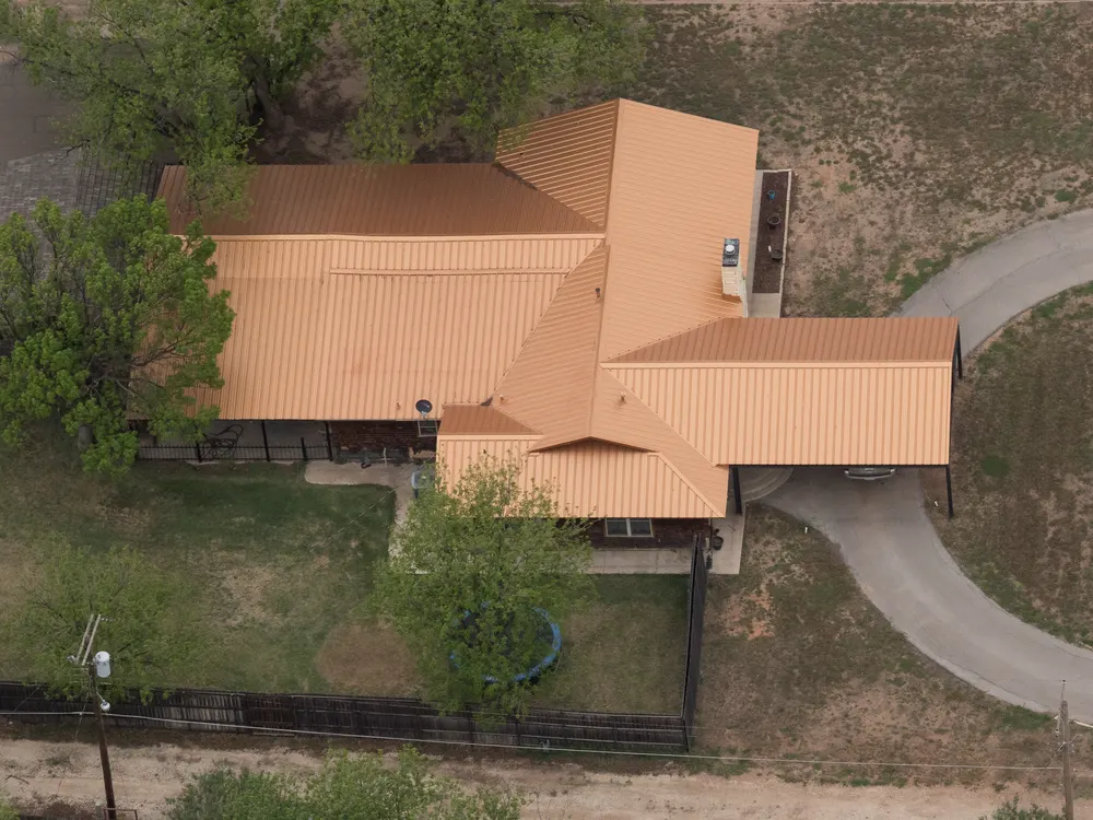 House with an orange metal roof and a curved driveway, seen from above