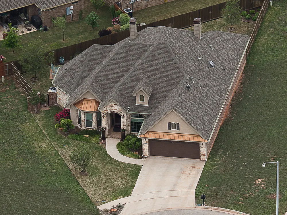 Large house with a gray shingle roof and a front garage, seen from above
